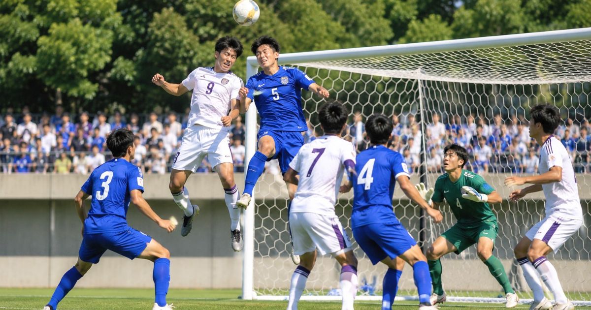 関西学生サッカー1部の公式戦で、ゴール前のクロスボールを選手が空中で競り合う様子