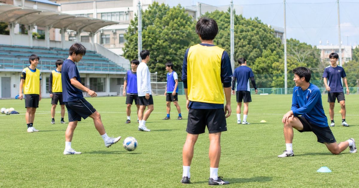関西学生サッカー2部の大学選手が、大学グラウンドでリラックスしながら練習に取り組む様子