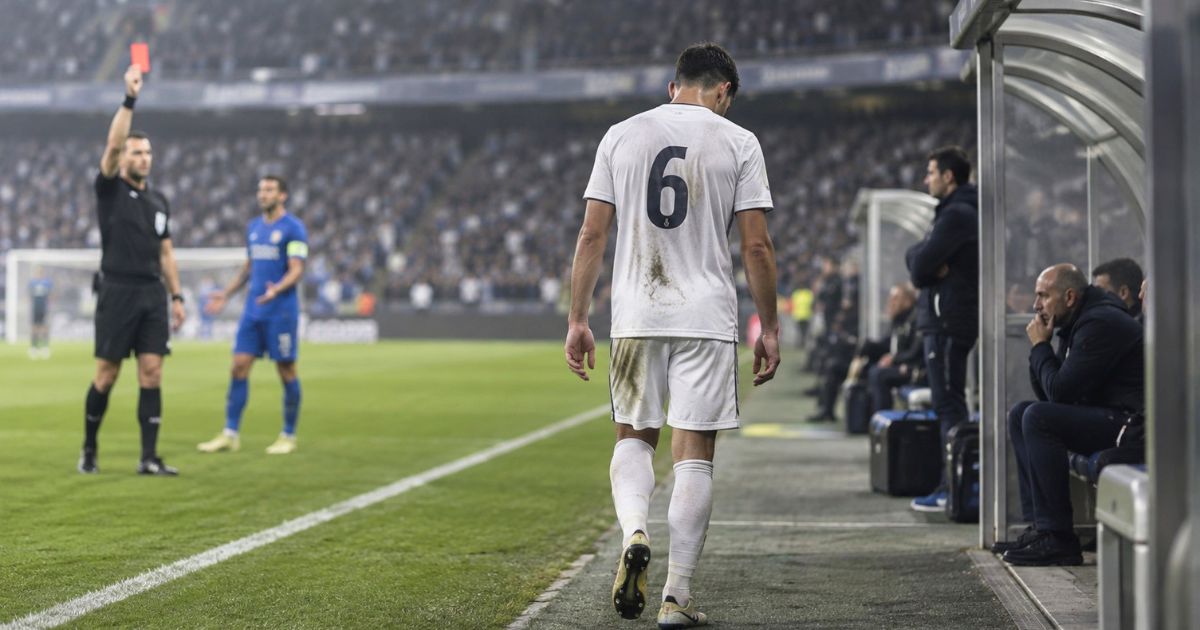 レッドカードを受けて退場し、ベンチ脇を下がっていくサッカー選手の後ろ姿