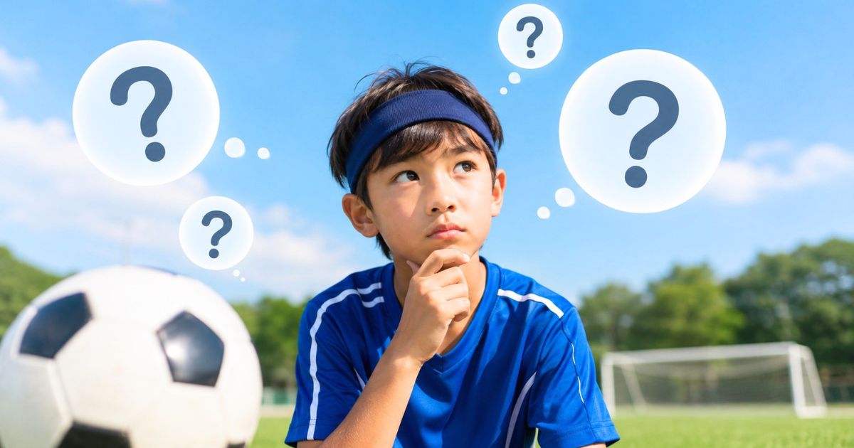 サッカー場でヘアバンドを着けた少年選手が、ボールのそばでルールに関する疑問を考えている様子