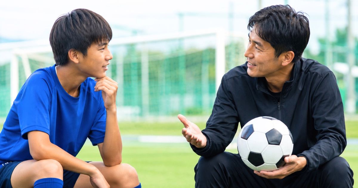 高校サッカー推薦について、グラウンドでコーチに質問する中学生のサッカー選手