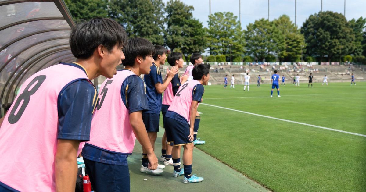 高校サッカーの公式戦で、ベンチから声援を送る控え選手たち