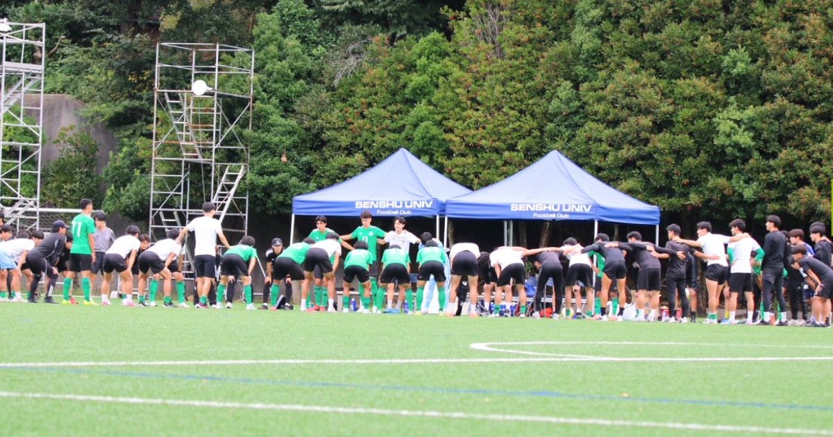 専修大学サッカー部の選手たちがグラウンドで円陣を組む練習風景