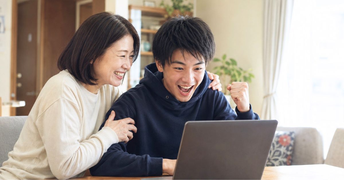大学合格をパソコンで確認し母親と喜ぶ大学サッカー部入部希望の高校生