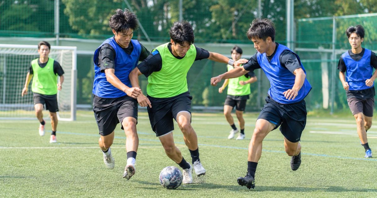大学サッカー部のセレクションでビブスを着た選手たちがミニゲームでボールを競り合う場面
