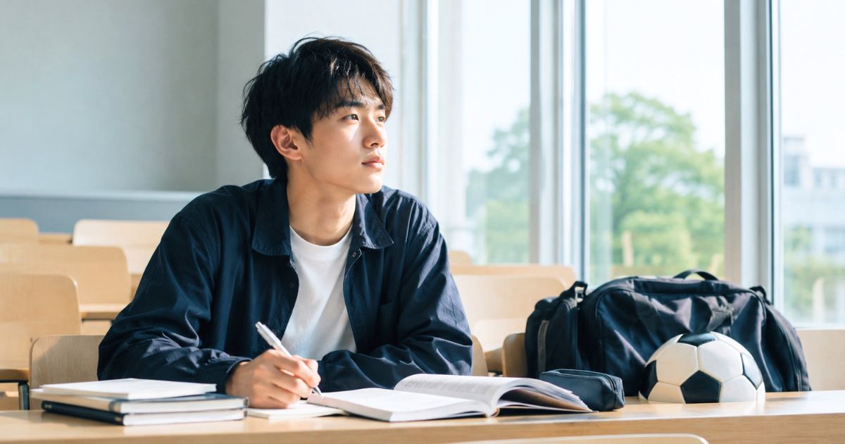 大学の講義室で勉強しながらサッカー部入部を考える一般入試志望の学生
