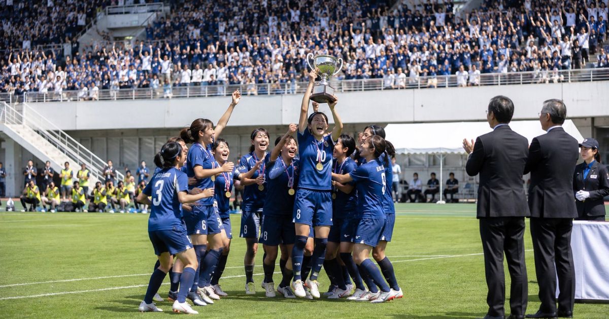 大学女子サッカーの全国大会で優勝し、観客と大会関係者の前でトロフィーを掲げて喜ぶ女子大学生選手たち