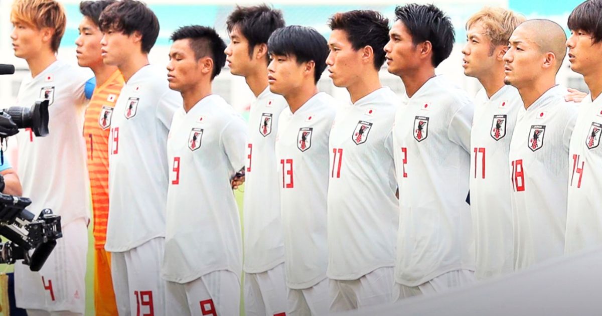 白い日本代表ユニフォームを着て試合前に整列する背番号付きのサッカー選手たち