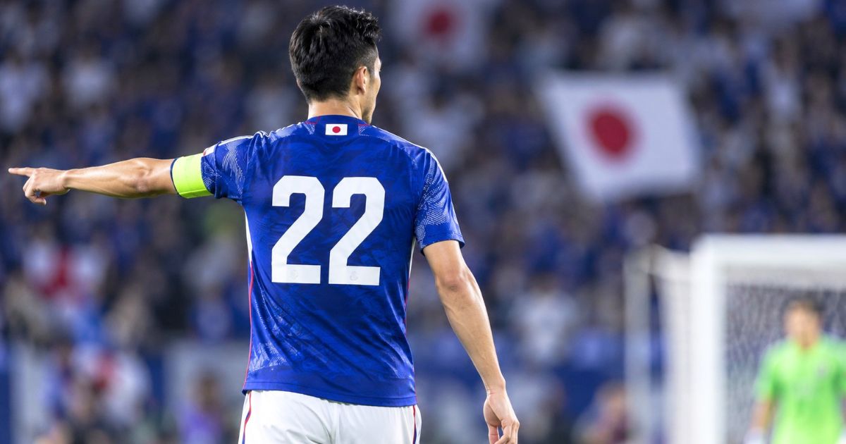 日本代表の青いユニフォームで背番号22を着けた選手が、ピッチ上で味方へ指示を出す後ろ姿