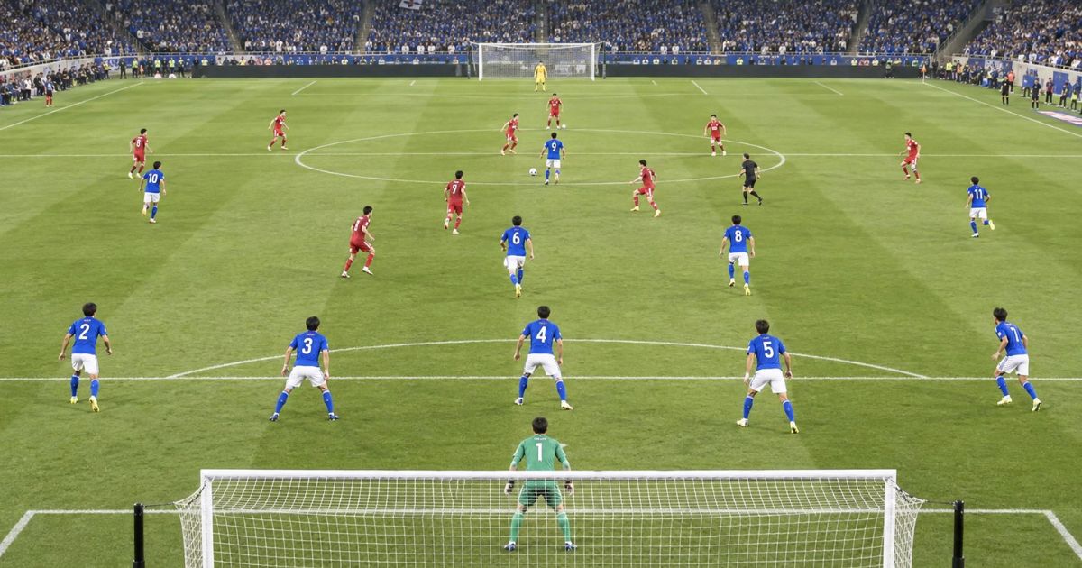 背番号1〜11番の選手が各ポジションに配置され、相手チームと対戦するサッカーの試合風景