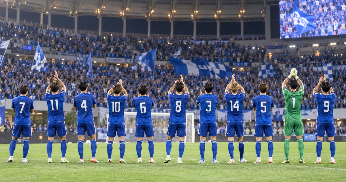 試合後に応援席へあいさつする背番号付きのサッカー選手11人の後ろ姿