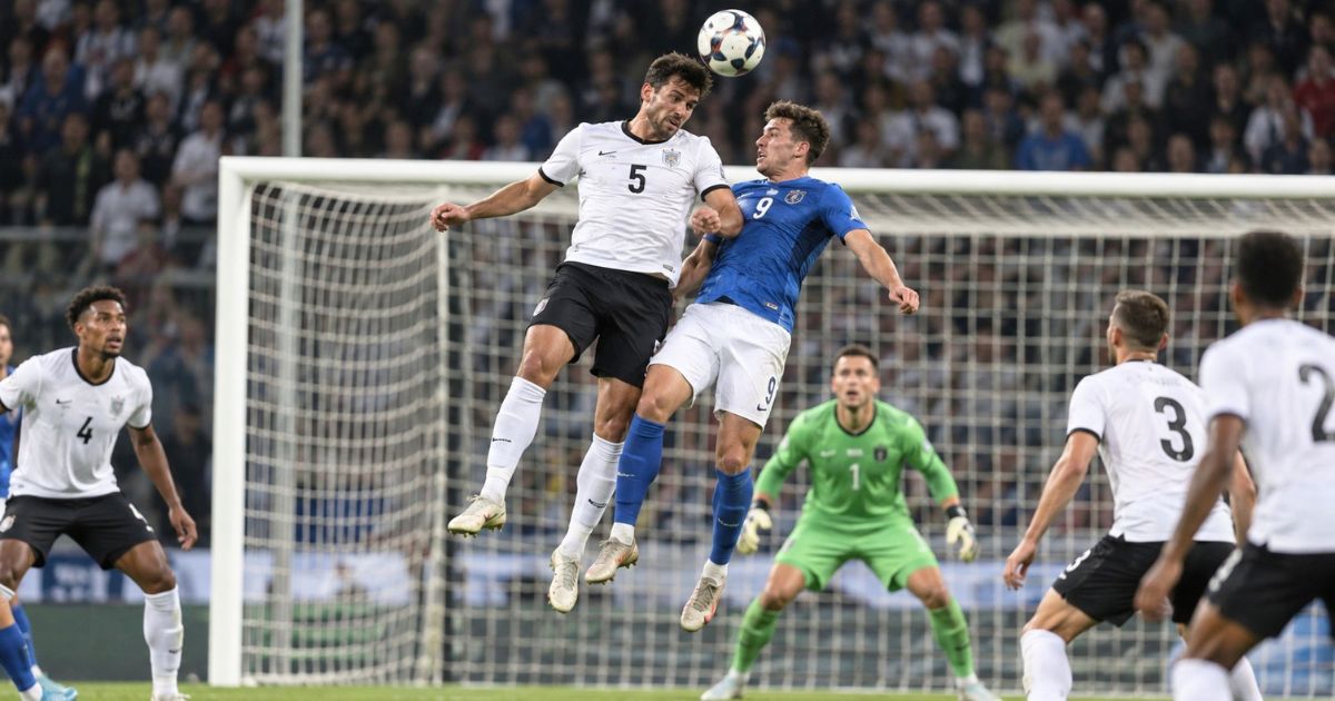 自陣ゴール前で相手FWとハイボールを競り合うサッカー背番号5のDFとゴールキーパー