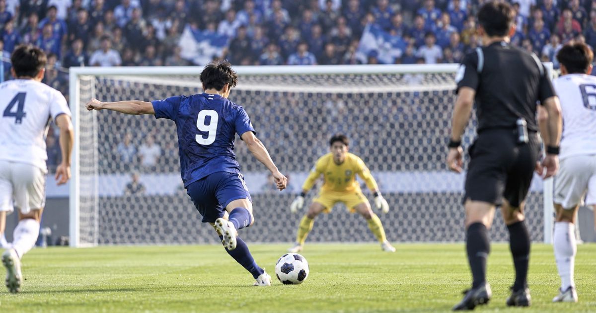 相手ゴール正面でGKに向かってシュートを放つ背番号9のサッカー選手