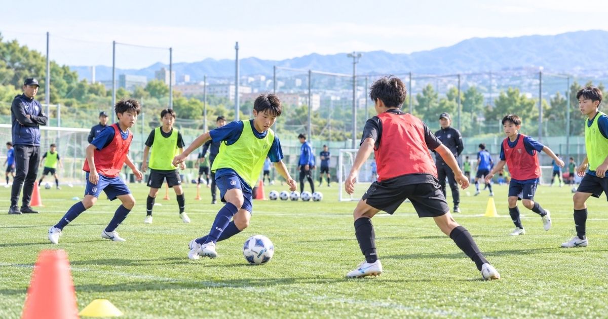 サッカーのトレセンで、コーチが見守る中、育成年代の選手たちがビブスを着て実戦形式の練習をする様子
