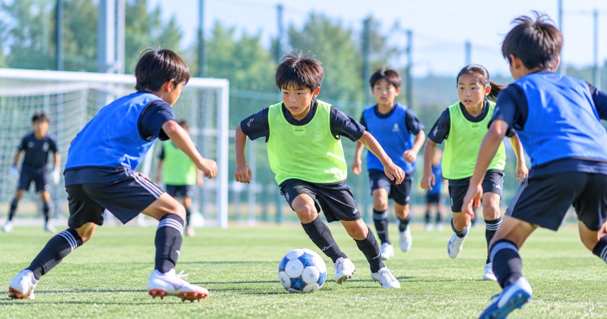U12年代の日本人選手たちがビブスを着てミニゲームでボールを競り合うサッカー練習風景