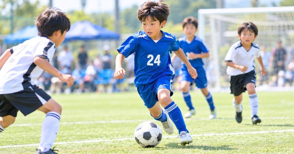 少年サッカーの試合で、背番号24の青いユニフォームを着た選手が相手をかわしながらドリブルする場面