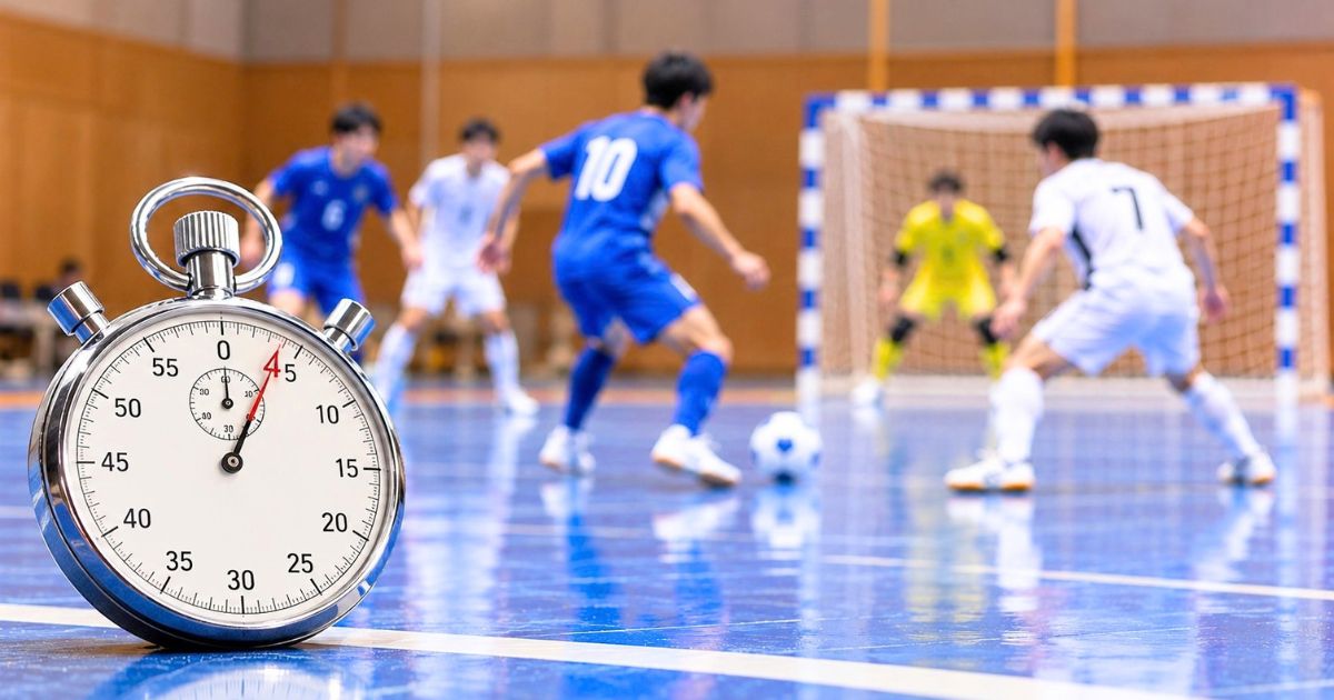 4秒を示すアナログストップウォッチと、背景で行われている室内フットサルの試合シーン
