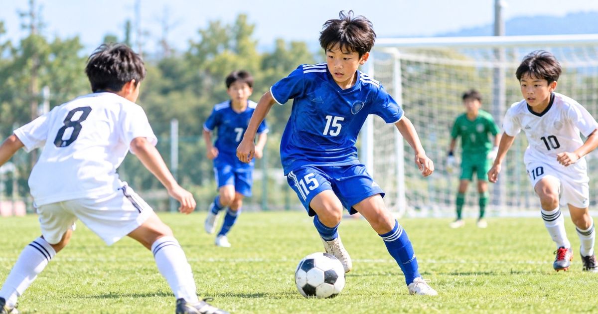 背番号15のユニフォームを着た少年サッカー選手が、試合でドリブルする様子